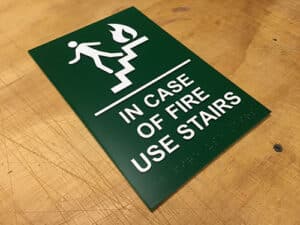 ADA-compliant green and white sign indicating "IN CASE OF FIRE USE STAIRS".