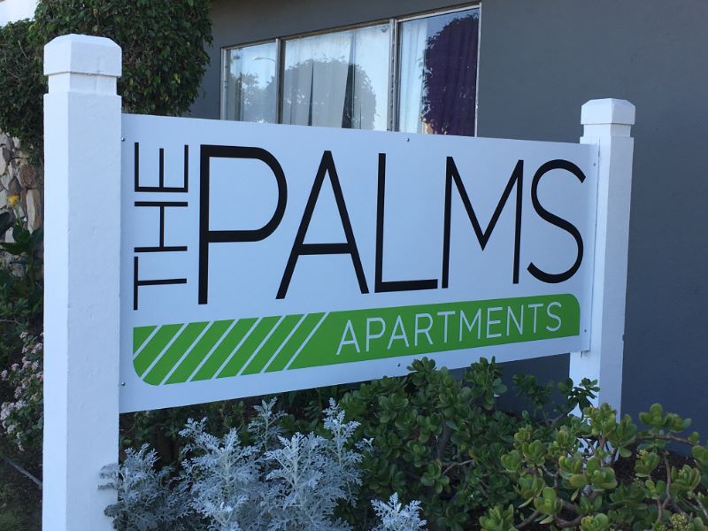 Modern post and panel outdoor sign for The Palms Apartments featuring the complex name in a clear, contemporary font with a subtle graphic element, designed to enhance visibility and brand the property.